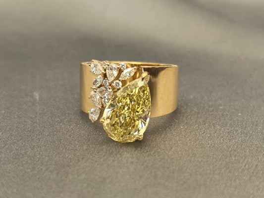 5.5-carat yellow diamond as the center stone | accompanied by pear-shaped, marquise, and round small diamonds | set on an ultra-wide band | surrounded by pavé-set small diamonds | spectacular and luxurious | 18k gold