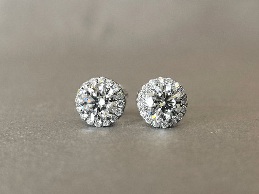 Round laboratory diamond stud earrings, surrounded by a circle of small diamonds, resembling a flower.