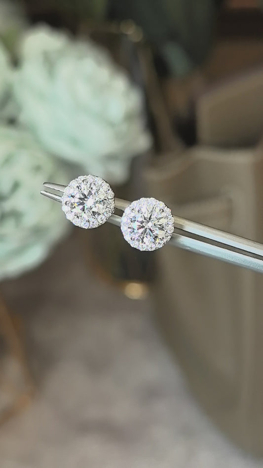 Round laboratory diamond stud earrings, surrounded by a circle of small diamonds, resembling a flower.